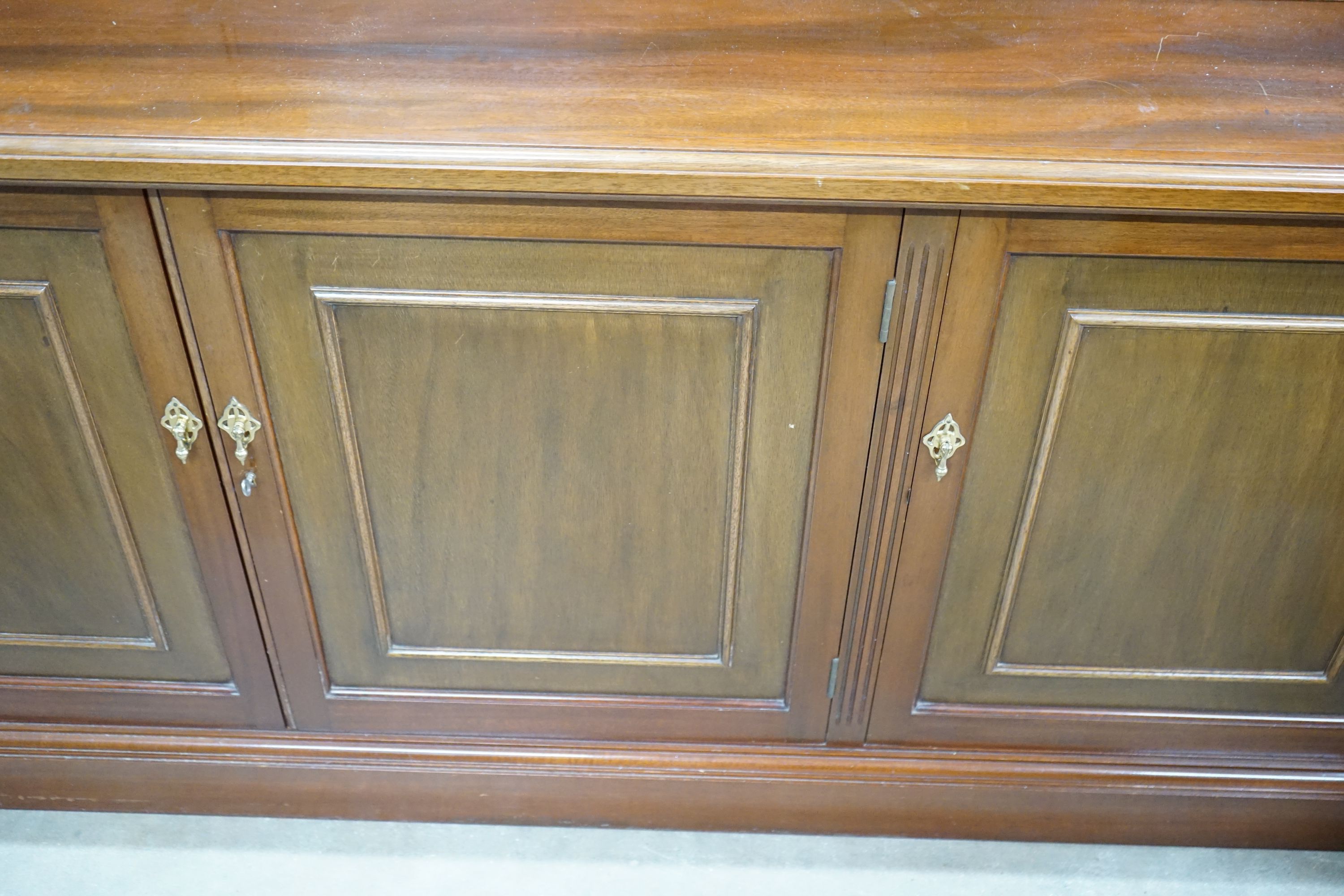 A Victorian style four section mahogany library bookcase, the upper section fitted clear glazed doors above further panelled doors on plinth base, length 216cm, depth 51cm, height 215cm